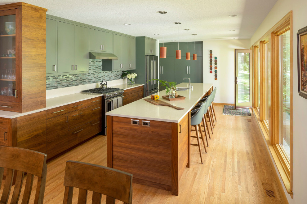 Photo of a large midcentury galley eat-in kitchen in Other with an undermount sink, flat-panel cabinets, green cabinets, wood benchtops, beige splashback, stainless steel appliances, light hardwood floors, with island and beige benchtop.