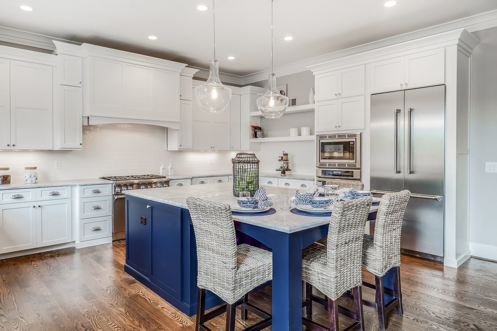 Photo of a large arts and crafts u-shaped eat-in kitchen in DC Metro with a farmhouse sink, flat-panel cabinets, white cabinets, quartzite benchtops, white splashback, subway tile splashback, stainless steel appliances, dark hardwood floors, with island and brown floor.