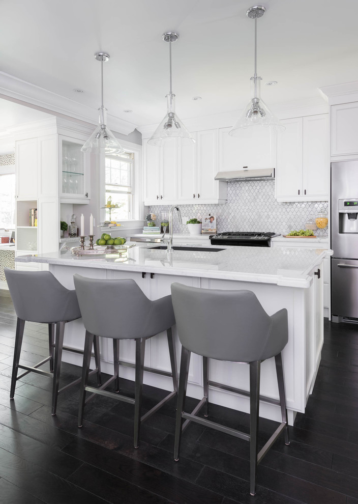 Inspiration for a mid-sized transitional galley open plan kitchen in Toronto with recessed-panel cabinets, white cabinets, marble benchtops, white splashback, stone tile splashback, stainless steel appliances, with island, an undermount sink and dark hardwood floors.