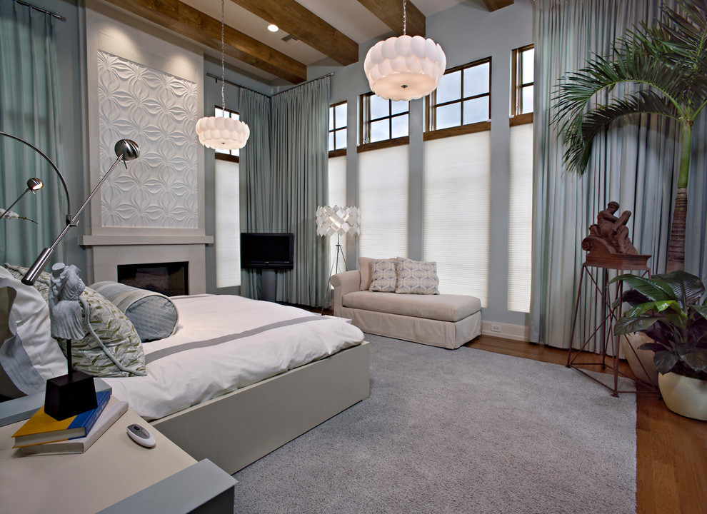 Tropical bedroom in Orlando with grey walls, medium hardwood floors and a standard fireplace.