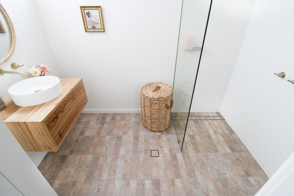 Exempel på ett litet minimalistiskt badrum med dusch, med släta luckor, skåp i mörkt trä, en öppen dusch, en toalettstol med hel cisternkåpa, vit kakel, keramikplattor, vita väggar, klinkergolv i porslin, ett fristående handfat, träbänkskiva, flerfärgat golv och med dusch som är öppen