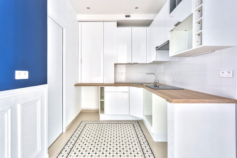 Mid-sized traditional l-shaped eat-in kitchen in Paris with beaded inset cabinets, white cabinets, wood benchtops, white splashback, ceramic splashback, stainless steel appliances, cement tiles, no island, blue floor and brown benchtop.