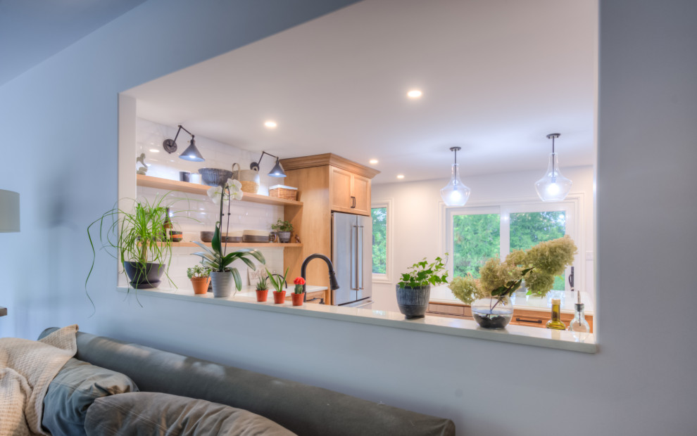 Inspiration for a transitional l-shaped kitchen remodel in Toronto with an undermount sink, shaker cabinets, light wood cabinets, white backsplash, stainless steel appliances, an island and white countertops