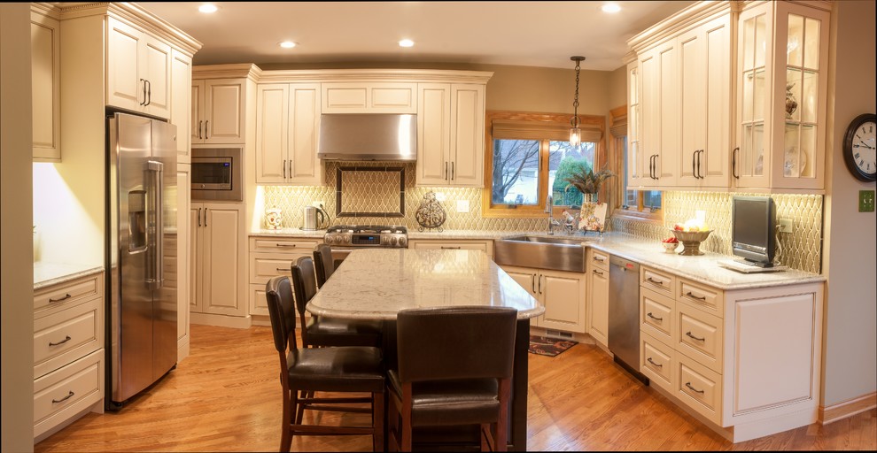 Large traditional u-shaped eat-in kitchen in Chicago with a farmhouse sink, raised-panel cabinets, white cabinets, granite benchtops, grey splashback, ceramic splashback, stainless steel appliances, medium hardwood floors, with island and brown floor.