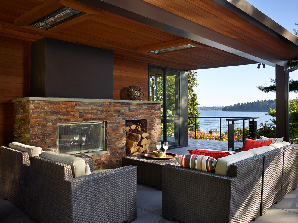 Mid-sized contemporary backyard deck in Seattle with a roof extension and with fireplace.