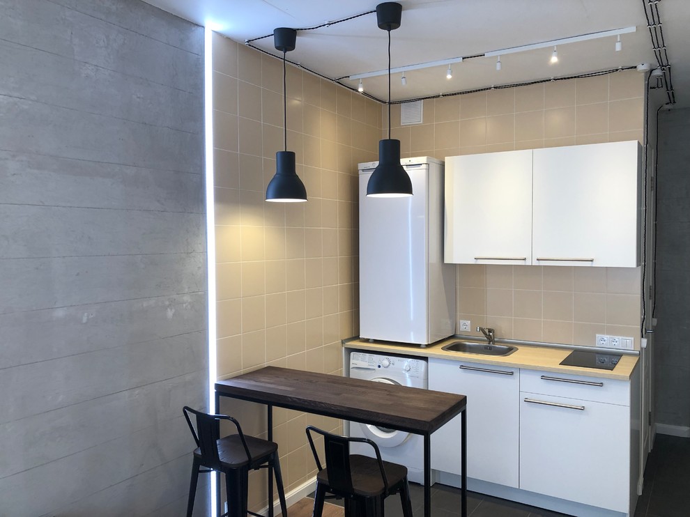 Design ideas for a small contemporary single-wall eat-in kitchen in Moscow with an undermount sink, flat-panel cabinets, white cabinets, wood benchtops, orange splashback, ceramic splashback, white appliances, porcelain floors, with island, grey floor and brown benchtop.