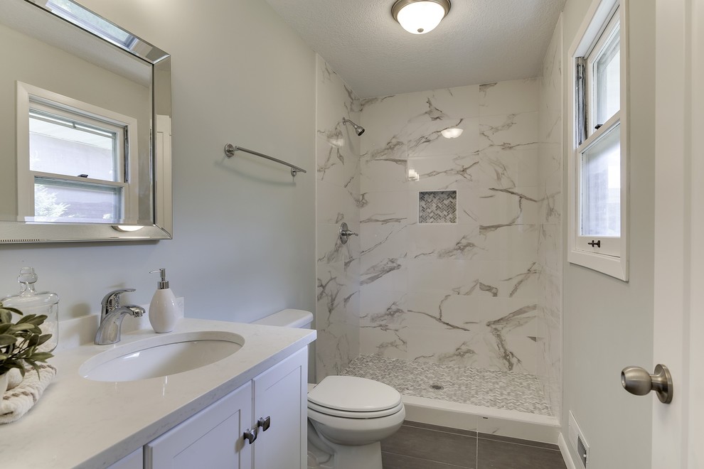 Small transitional master bathroom in Minneapolis with shaker cabinets, white cabinets, an alcove shower, a one-piece toilet, multi-coloured tile, porcelain tile, blue walls, porcelain floors, an undermount sink, engineered quartz benchtops, black floor, an open shower and white benchtops.