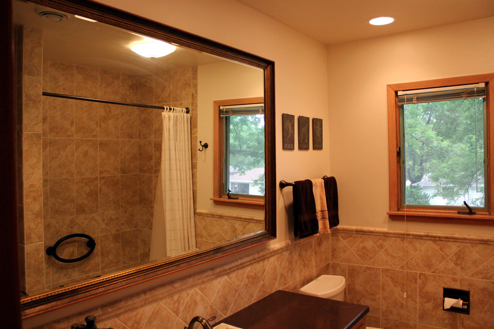 Inspiration for a mid-sized transitional 3/4 beige tile and ceramic tile alcove bathtub remodel with a two-piece toilet, beige walls, quartz countertops and black countertops