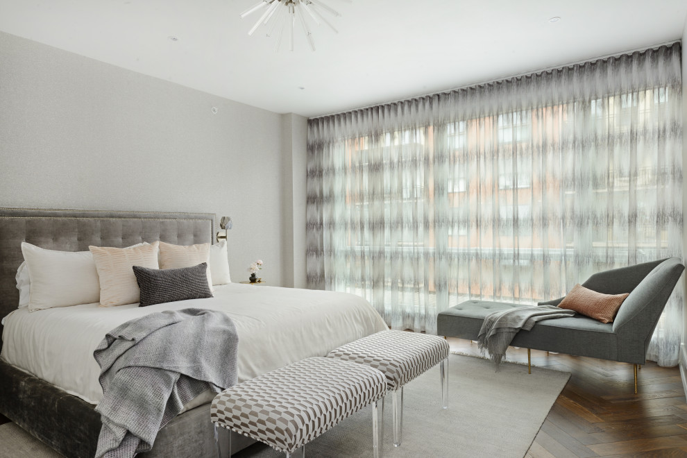 Eclectic master bedroom in New York with grey walls and medium hardwood floors.
