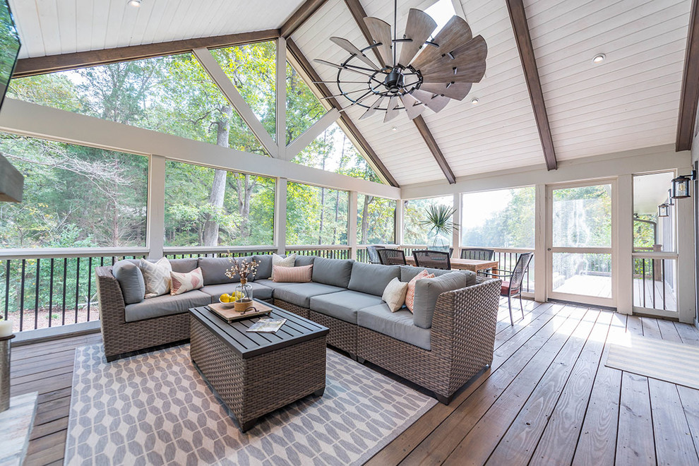 This is an example of a large country sunroom in Atlanta with medium hardwood floors, a standard fireplace, a brick fireplace surround, a skylight and brown floor.