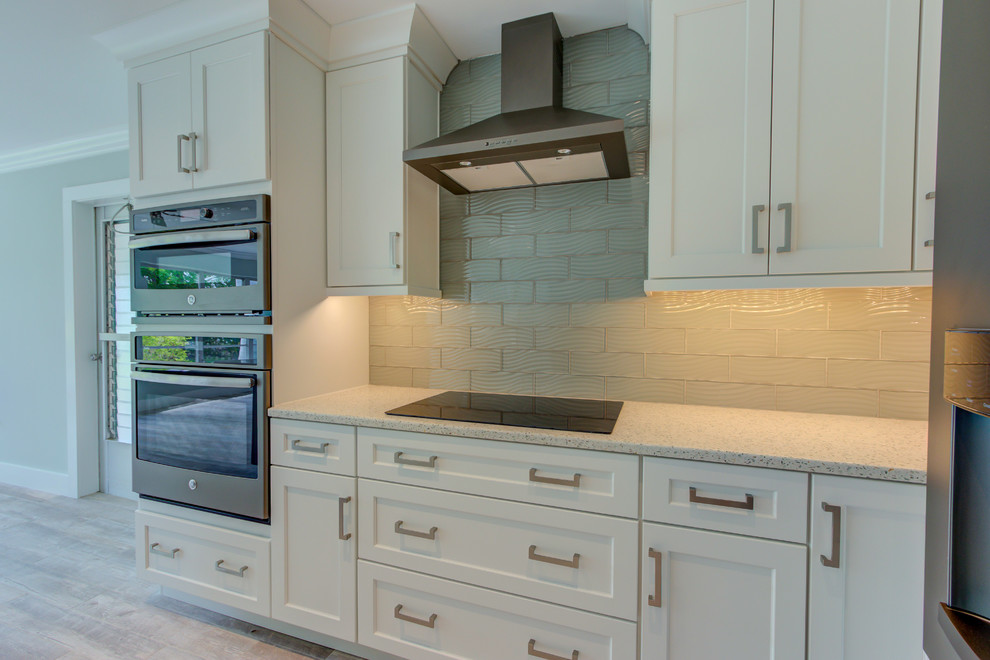Inspiration for a large transitional l-shaped ceramic tile and gray floor home design remodel with an undermount sink, shaker cabinets, white cabinets, recycled glass countertops, blue backsplash, glass tile backsplash, stainless steel appliances, an island and white countertops