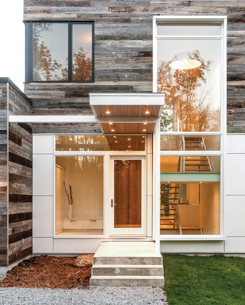 Inspiration for a large contemporary front door in Montreal with a single front door, a glass front door, white walls and light hardwood floors.