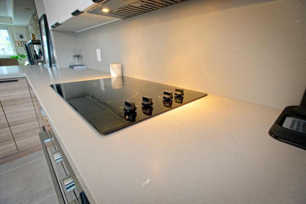 Exempel på ett mellanstort minimalistiskt grå grått kök, med en undermonterad diskho, släta luckor, skåp i ljust trä, bänkskiva i kvartsit, grått stänkskydd, stänkskydd i porslinskakel, rostfria vitvaror, klinkergolv i keramik, en köksö och grått golv