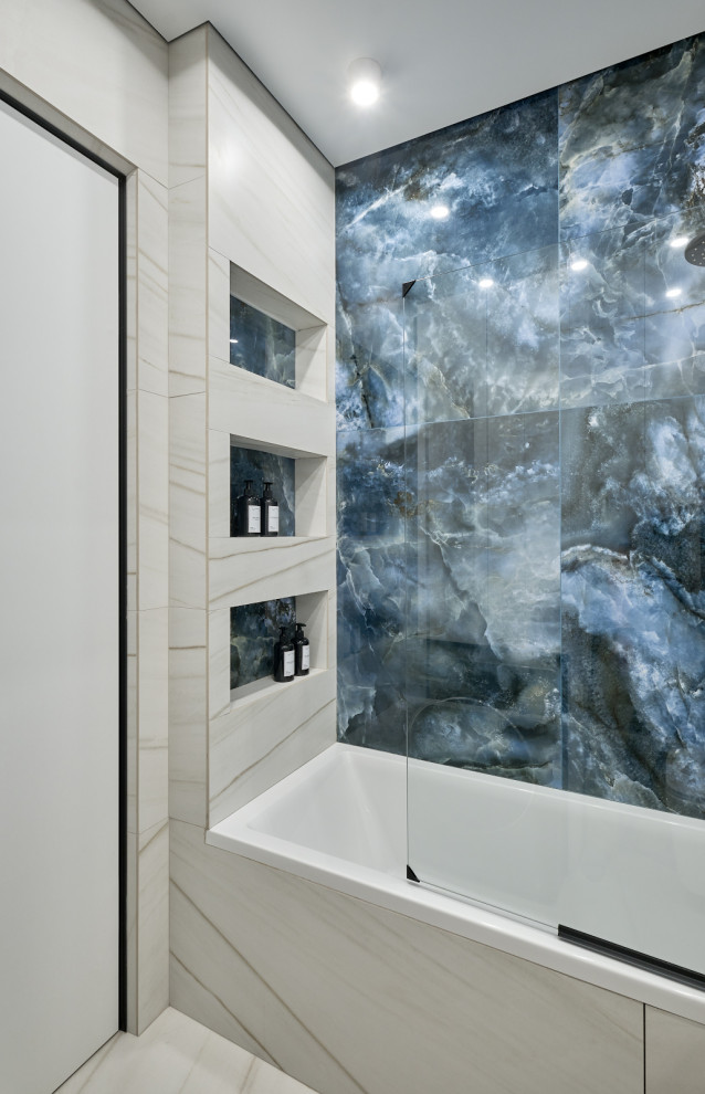 На фото: главная ванная комната среднего размера в современном стиле с полновстраиваемой ванной, душем над ванной, инсталляцией, синей плиткой, белой плиткой, керамогранитной плиткой, синими стенами, настольной раковиной, столешницей из оникса, душем с распашными дверями, синей столешницей и тумбой под одну раковину с