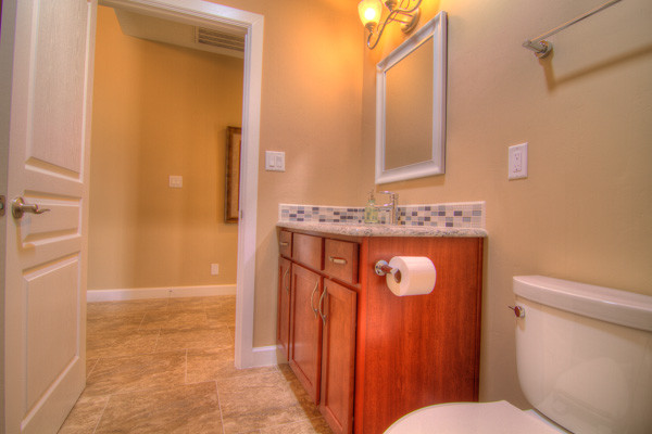 This is an example of a mid-sized traditional 3/4 bathroom in Albuquerque with an undermount sink, shaker cabinets, medium wood cabinets, granite benchtops, an open shower, a two-piece toilet, multi-coloured tile, ceramic tile, blue walls and ceramic floors.