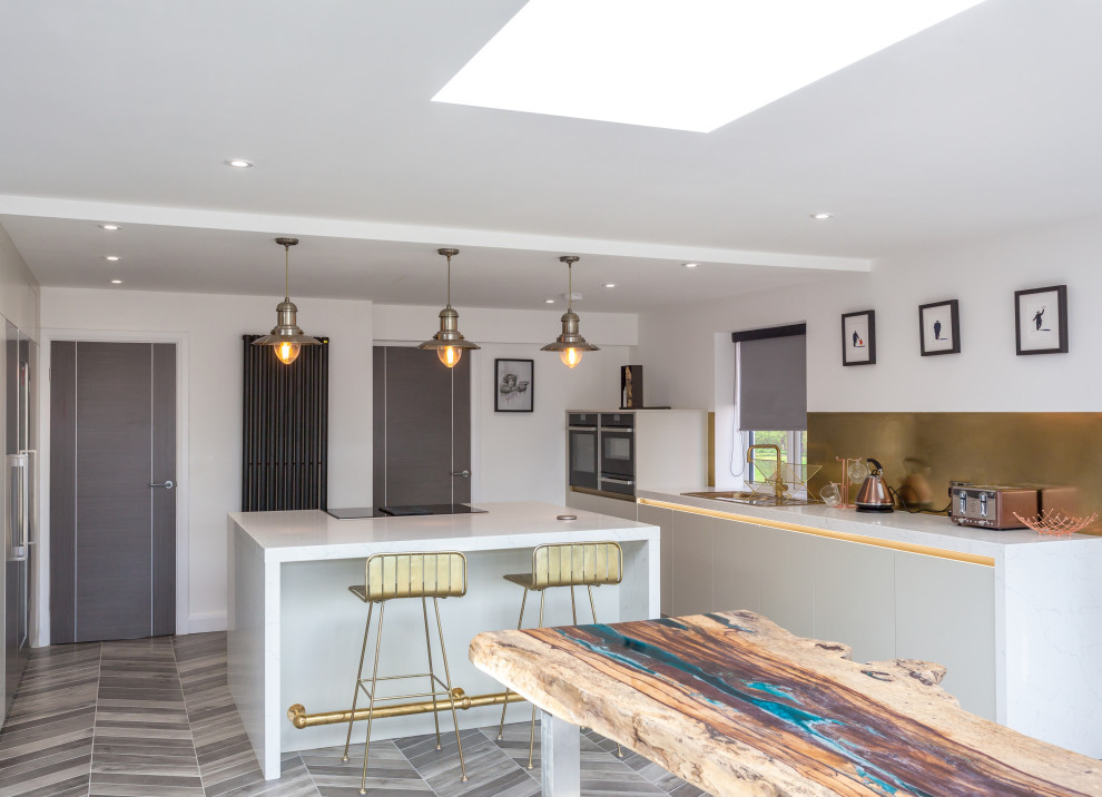 Inspiration for a large contemporary open plan kitchen in Manchester with an integrated sink, flat-panel cabinets, beige cabinets, marble benchtops, metallic splashback, metal splashback, stainless steel appliances, porcelain floors, with island, multi-coloured floor and white benchtop.