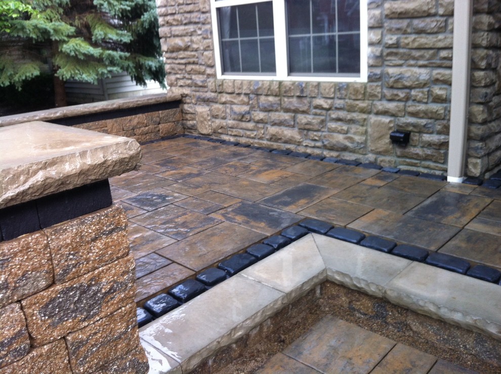 This is an example of a mid-sized traditional patio in Columbus with concrete pavers and no cover.