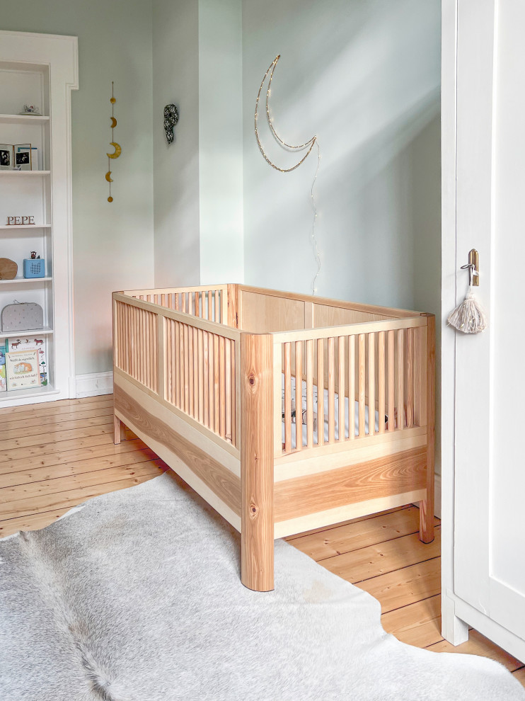 高級な小さなモダンスタイルのおしゃれな赤ちゃん部屋 (緑の壁、淡色無垢フローリング、男女兼用、ベージュの床) の写真