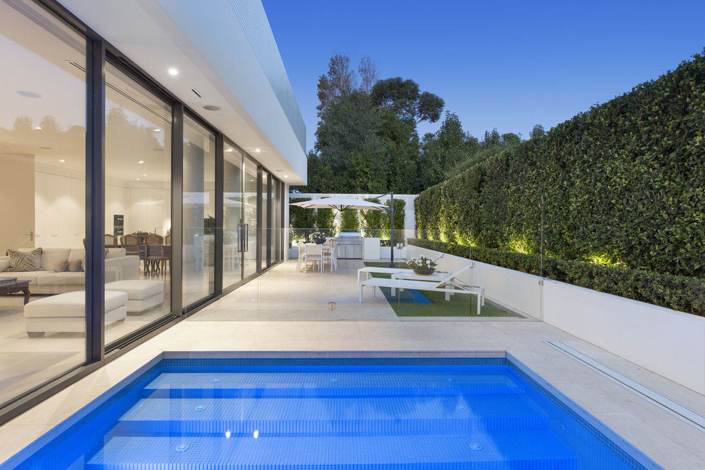 This is an example of a contemporary side yard formal garden in Melbourne with natural stone pavers.
