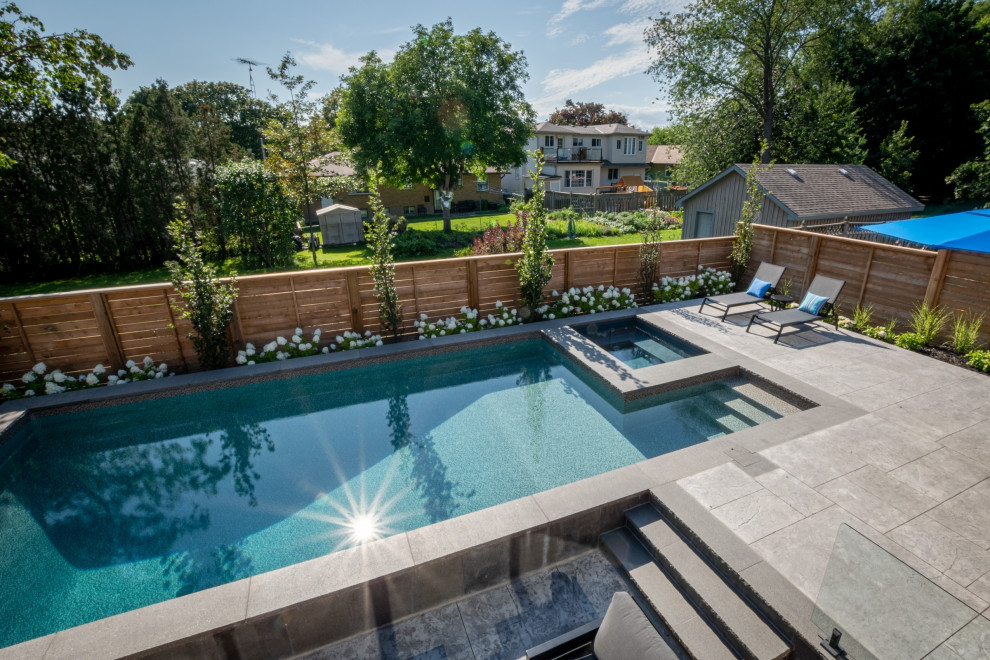 This is an example of a mid-sized backyard rectangular pool in Toronto with a hot tub and stamped concrete.