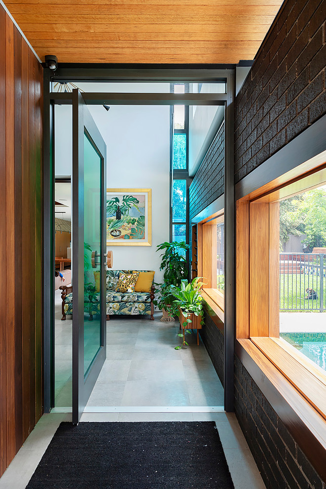 Photo of a midcentury entry hall in Perth with concrete floors, a pivot front door and a glass front door.