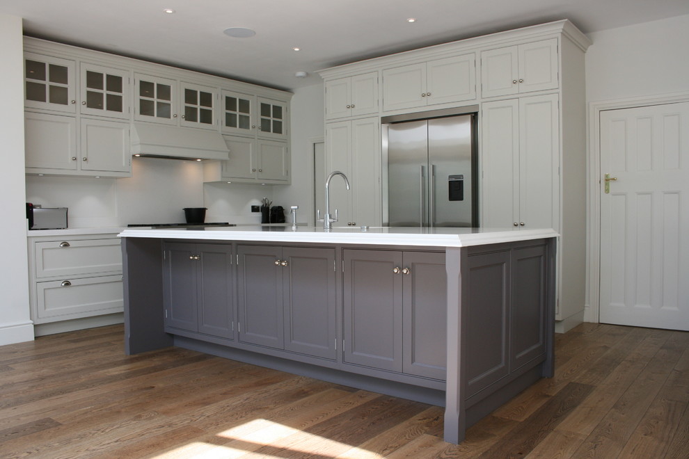 Photo of a large transitional l-shaped eat-in kitchen in London with an undermount sink, quartz benchtops, stainless steel appliances, dark hardwood floors, with island, beaded inset cabinets and grey cabinets.