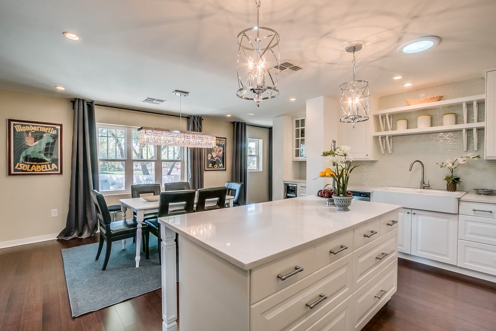 Inspiration for a mid-sized transitional u-shaped medium tone wood floor and brown floor open concept kitchen remodel in Phoenix with raised-panel cabinets, white cabinets, quartz countertops, white backsplash, matchstick tile backsplash, stainless steel appliances and an island