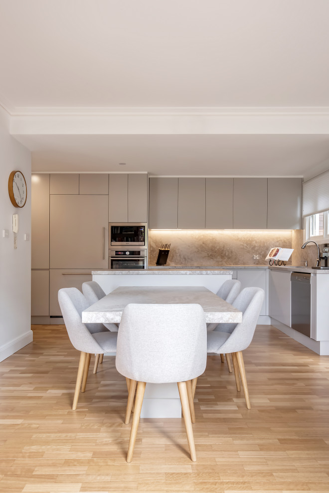 Mid-sized trendy l-shaped light wood floor open concept kitchen photo in Sydney with a drop-in sink, flat-panel cabinets, beige cabinets, quartz countertops, beige backsplash, quartz backsplash, stainless steel appliances, an island and beige countertops