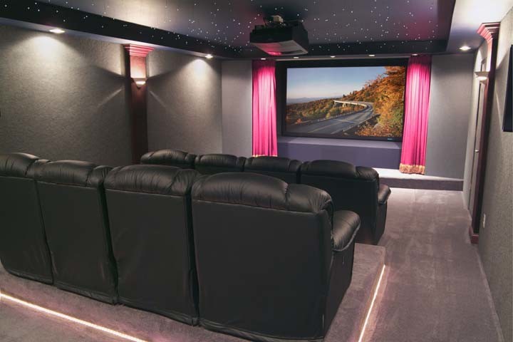 Mid-sized traditional enclosed home theatre in Other with grey walls, carpet and a projector screen.