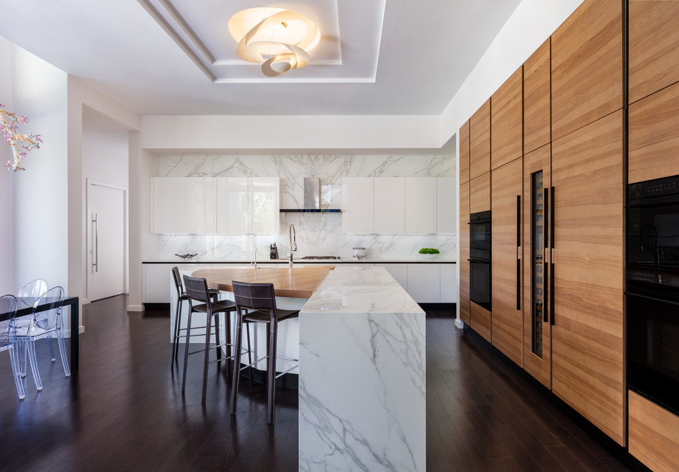 Contemporary eat-in kitchen in Hawaii with flat-panel cabinets, white cabinets, white splashback, stone slab splashback, panelled appliances, dark hardwood floors, with island, brown floor and white benchtop.