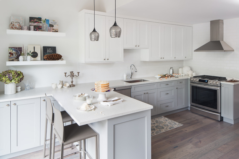 Mid-sized transitional l-shaped light wood floor eat-in kitchen photo in Vancouver with an undermount sink, shaker cabinets, gray cabinets, white backsplash, subway tile backsplash, stainless steel appliances, a peninsula and quartzite countertops