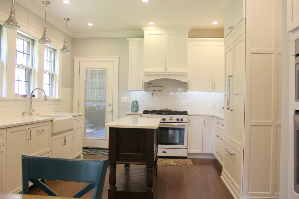 Eat-in kitchen - mid-sized transitional u-shaped medium tone wood floor and brown floor eat-in kitchen idea with a farmhouse sink, shaker cabinets, white cabinets, quartz countertops, white backsplash, subway tile backsplash, white appliances and an island