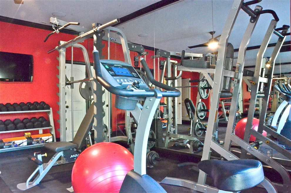 Inspiration for a large contemporary home weight room in Charlotte with red walls and black floor.