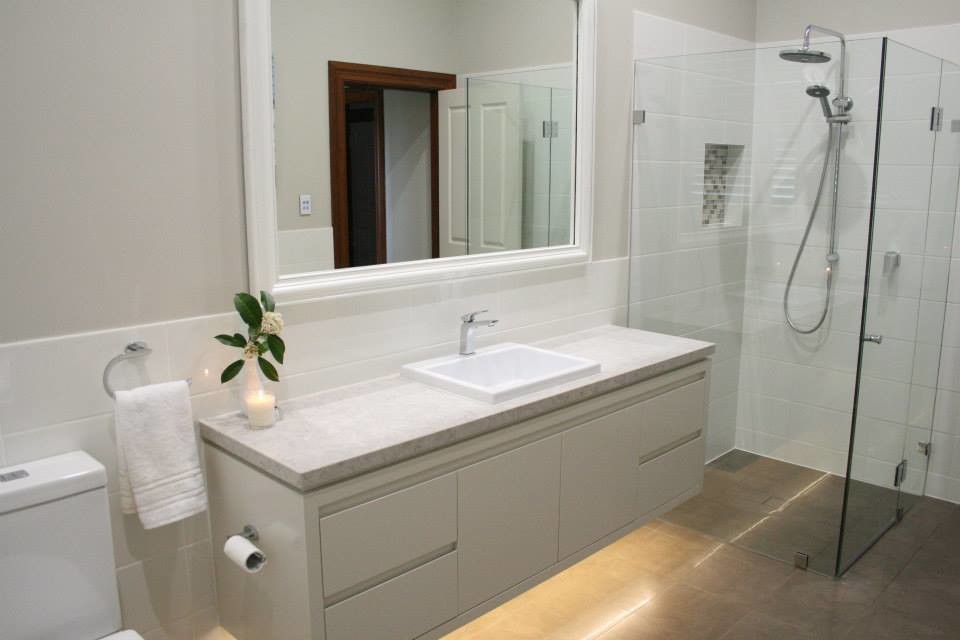This is an example of a large contemporary kids bathroom in Sydney with flat-panel cabinets, white cabinets, a wall-mount toilet, white tile, ceramic tile, white walls, a drop-in sink, engineered quartz benchtops, a drop-in tub, a corner shower and ceramic floors.