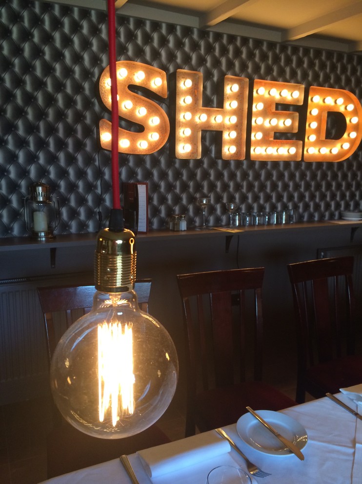 Medium sized industrial dining room in London with banquette seating, vinyl flooring, wallpapered walls and feature lighting.
