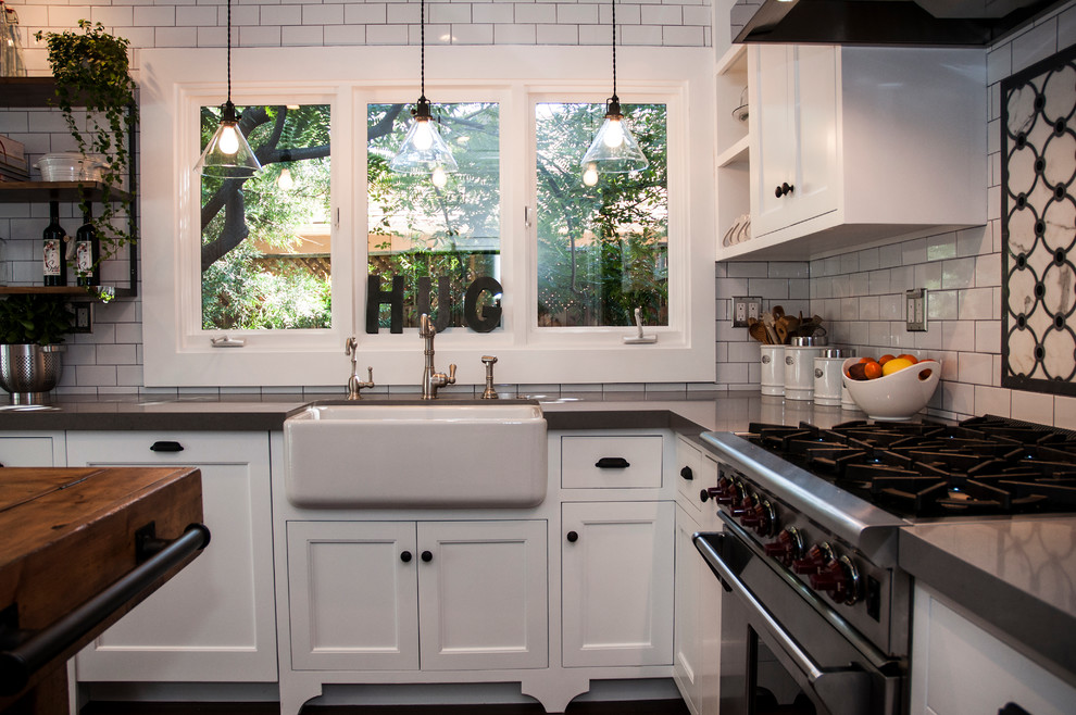 Inspiration for a mid-sized eclectic u-shaped separate kitchen in Los Angeles with a farmhouse sink, shaker cabinets, white cabinets, quartz benchtops, white splashback, subway tile splashback, stainless steel appliances, dark hardwood floors, with island, brown floor and grey benchtop.