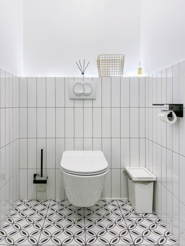 Modelo de aseo escandinavo pequeño con sanitario de pared, baldosas y/o azulejos blancos, baldosas y/o azulejos de cerámica, paredes blancas, suelo de baldosas de cerámica y lavabo suspendido