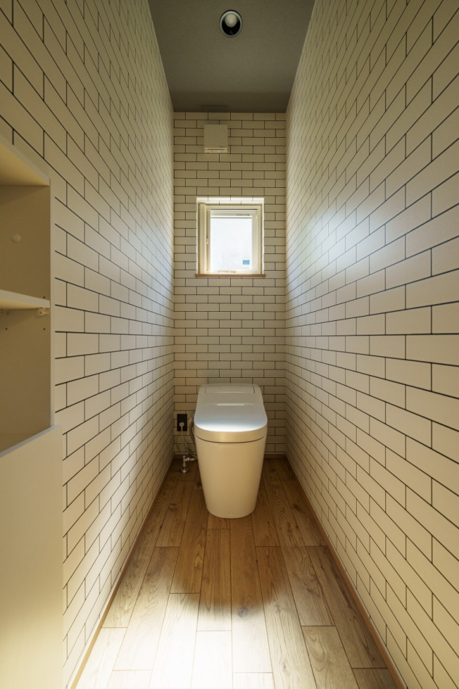 This is an example of a medium sized modern cloakroom in Other with a bidet, white walls, light hardwood flooring, beige floors, a feature wall, a wallpapered ceiling and wallpapered walls.