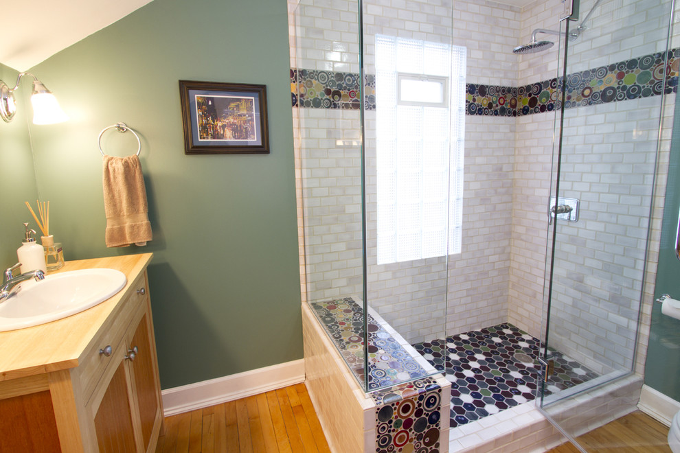 Mid-sized eclectic 3/4 bathroom in Minneapolis with a drop-in sink, recessed-panel cabinets, light wood cabinets, wood benchtops, a corner shower, a one-piece toilet, multi-coloured tile, ceramic tile, green walls, light hardwood floors, brown floor and a hinged shower door.