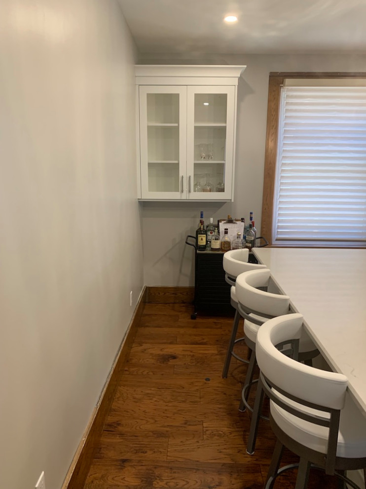 Small transitional galley medium tone wood floor open concept kitchen photo in Toronto with shaker cabinets, white cabinets, solid surface countertops, an island and white countertops