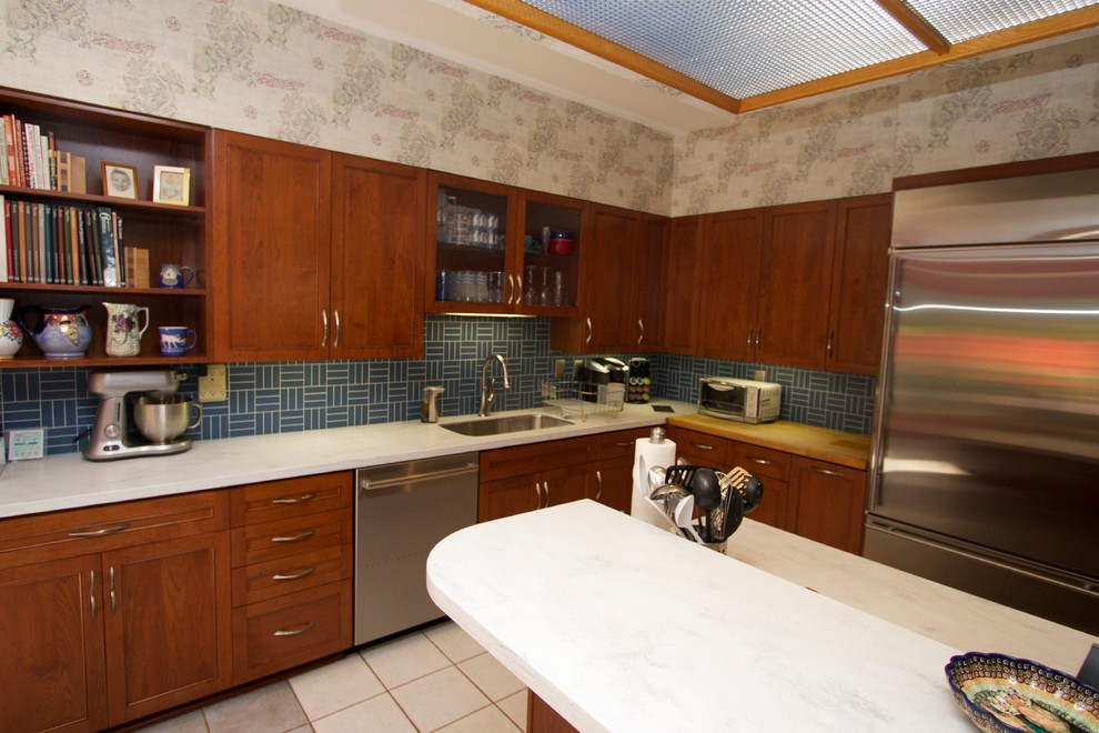 Inspiration for a transitional l-shaped ceramic tile open concept kitchen remodel in Baltimore with an undermount sink, recessed-panel cabinets, medium tone wood cabinets, solid surface countertops, blue backsplash, ceramic backsplash, stainless steel appliances and an island