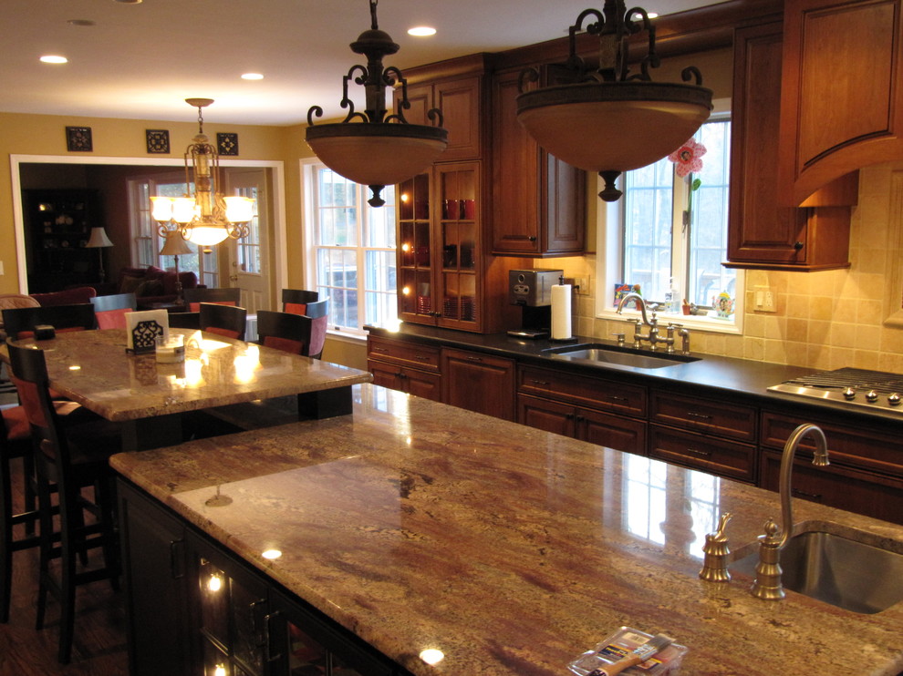 This is an example of a large traditional u-shaped eat-in kitchen in Jacksonville with a double-bowl sink, raised-panel cabinets, dark wood cabinets, granite benchtops, beige splashback, ceramic splashback, stainless steel appliances and with island.
