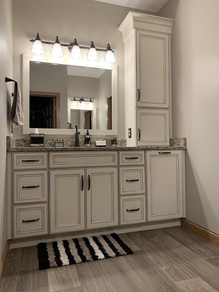 Home design - large transitional master beige tile and ceramic tile linoleum floor and brown floor home design idea with recessed-panel cabinets, white cabinets, a two-piece toilet, beige walls, an undermount sink, granite countertops, a hinged shower door and multicolored countertops