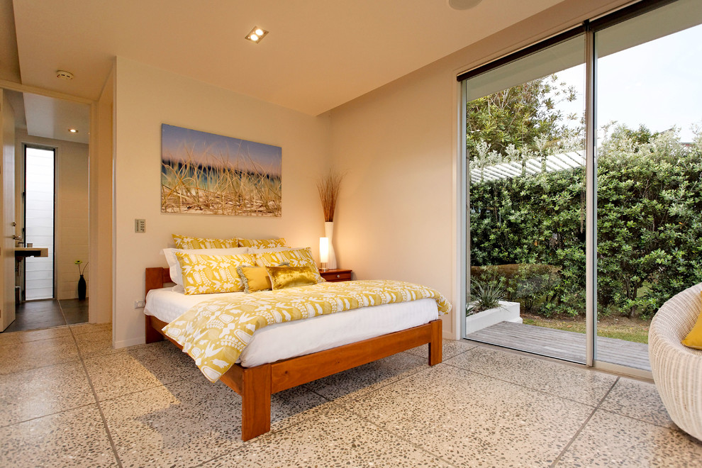 Photo of a mid-sized country master bedroom in Auckland with white walls, concrete floors and no fireplace.
