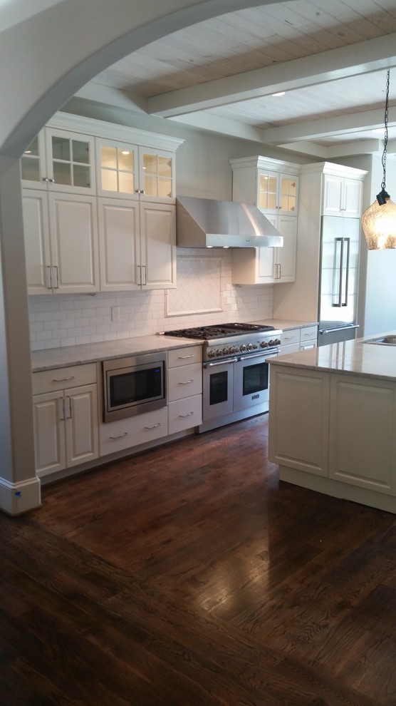 Inspiration for a mid-sized transitional u-shaped dark wood floor and brown floor eat-in kitchen remodel in Birmingham with raised-panel cabinets, white cabinets, white backsplash, subway tile backsplash, stainless steel appliances and an island