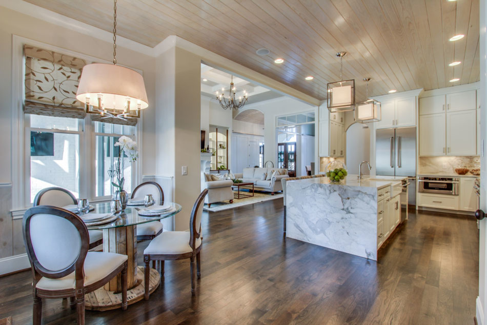 Photo of a large transitional l-shaped open plan kitchen in New Orleans with a farmhouse sink, shaker cabinets, white cabinets, marble benchtops, white splashback, stone slab splashback, stainless steel appliances, dark hardwood floors and with island.