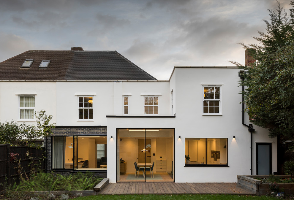 Mid-sized contemporary one-storey stucco yellow duplex exterior in London with a flat roof and a mixed roof.