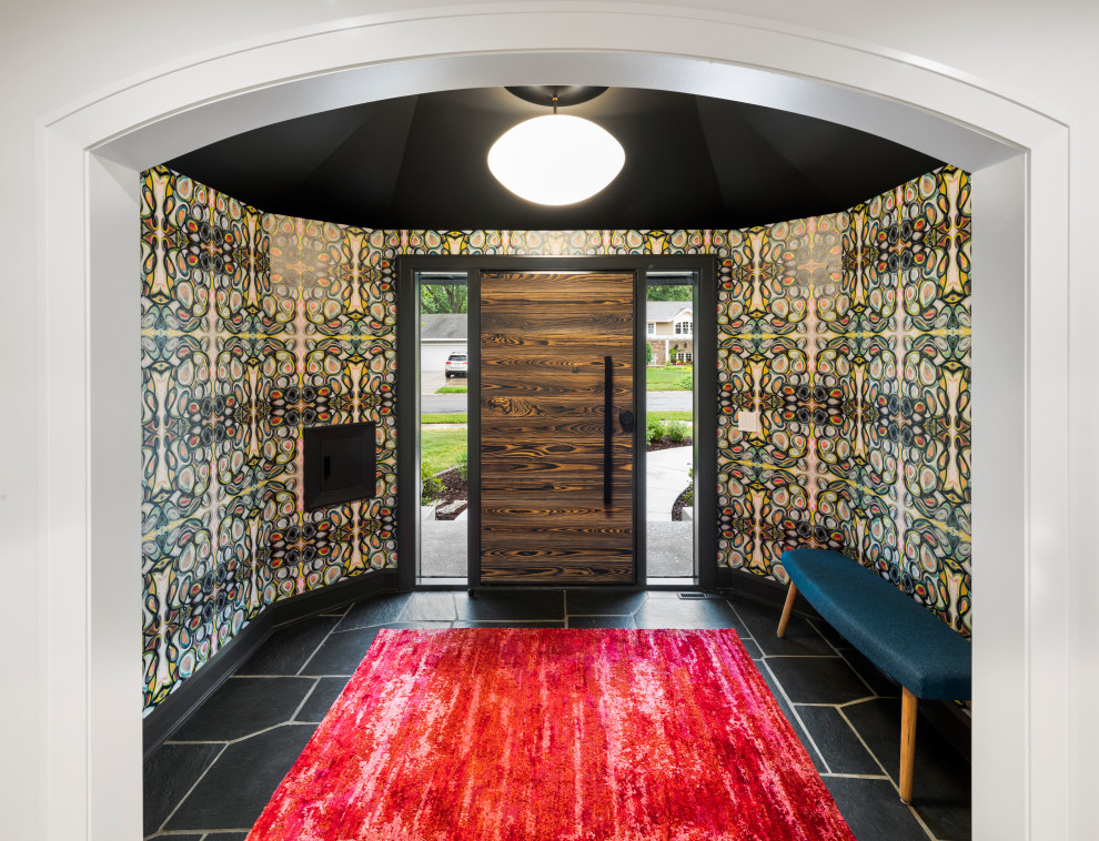 Réalisation d'une entrée design avec un mur multicolore, une porte simple, une porte en bois foncé, un sol noir, un plafond voûté et du papier peint.