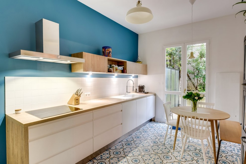 This is an example of a large scandinavian single-wall eat-in kitchen in Paris with laminate benchtops, white splashback, panelled appliances, flat-panel cabinets, a single-bowl sink, ceramic splashback, ceramic floors, no island and white cabinets.