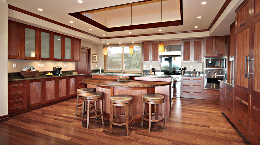 Photo of a mid-sized tropical single-wall separate kitchen in Hawaii with recessed-panel cabinets, medium wood cabinets, granite benchtops, stainless steel appliances, light hardwood floors, with island, beige floor and an undermount sink.
